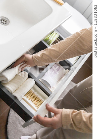 Top view of woman hands neatly organizing bathroom amenities and toiletries in drawer in bathroom. Top view of woman hands neatly organizing bathroom amenities and toiletries in drawer in bathroom. 118831062