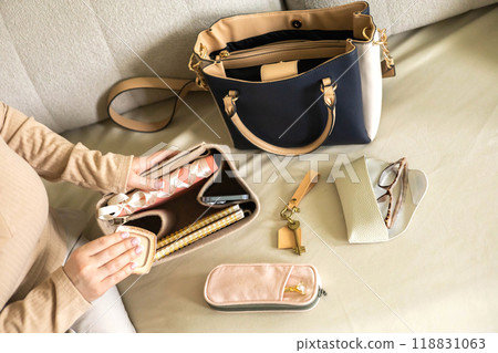 A young beautiful woman is collecting her women's bag. He puts away his diary, glasses, keys 118831063