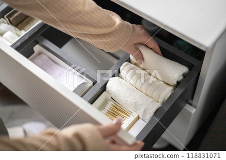 Top view of woman hands neatly organizing bathroom amenities and toiletries in drawer in bathroom. Top view of woman hands neatly organizing bathroom amenities and toiletries in drawer in bathroom. 118831071