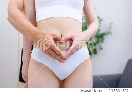 Couple supporting the woman's belly, couple making a heart shape with their hands, married couple, pregnancy support 118831822