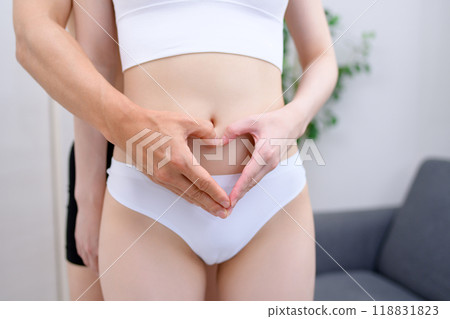 Couple supporting the woman's belly, couple making a heart shape with their hands, married couple, pregnancy support 118831823