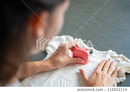 Close-up view of woman with a stamp with a name for signing children's things. Identification of personal clothing. 118832114