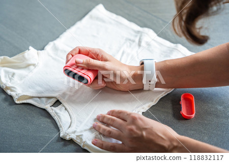 Close-up view of woman's hands with a stamp with a name for signing children's things. Identification of personal clothing. 118832117