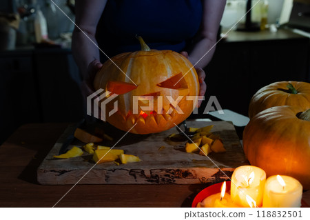A person is skillfully carving a pumpkin for halloween that has a face carved into it 118832501