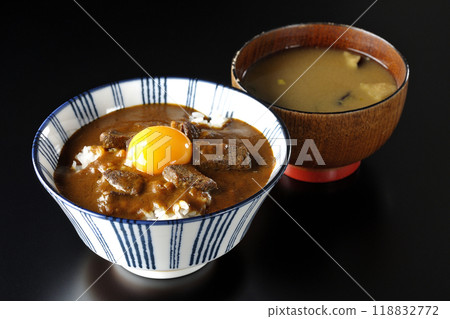 Tsukimi beef curry bowl and miso soup photographed against a black background 118832772