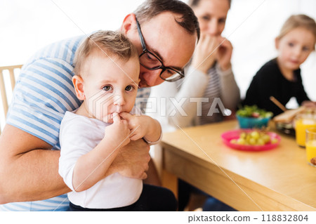 Parents with two children eating a tasty, healthy breakfast in the kitchen. Happy family moment. 118832804