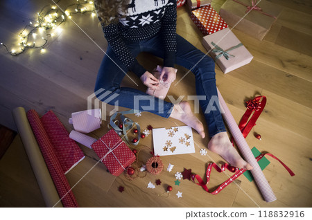 Close up on woman wrapping Christmas presents, sitting on the floor by Christmas tree. Preparing for Christmas Eve. Close up on woman wrapping Christmas presents, sitting on the floor by Christmas tree. Preparing for Christmas Eve. 118832916