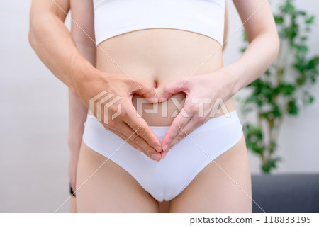 Couple supporting the woman's belly, man and woman making a heart shape with their hands, married couple, pregnancy support, real color 118833195