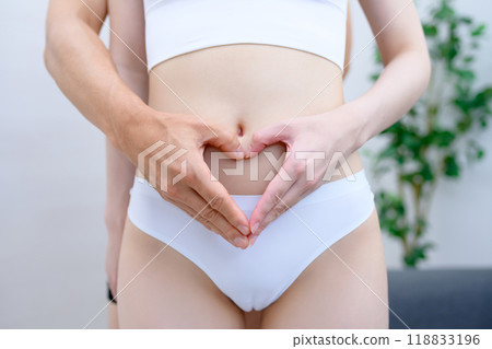 Couple supporting the woman's belly, couple making a heart shape with their hands, married couple, pregnancy support 118833196