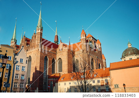 St Mary Basilica in Gdansk, Poland. Historical religious building facade. Towering Gothic architecture with spires, and clock against blue sky 118833403