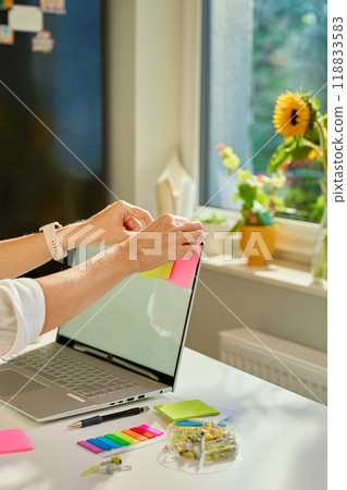 Woman is using sticky notes on her laptop screen to organize her work while working remotely from home. Concept of planning and task management in office work 118833583