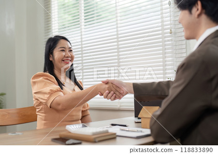 Smiling Client and Real Estate Agent Shaking Hands Post Deal Closure 118833890