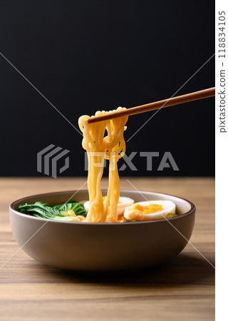 Spicy noodles soup with egg, seaweed and bok choy eating by chopsticks, Asian noodles style 118834105