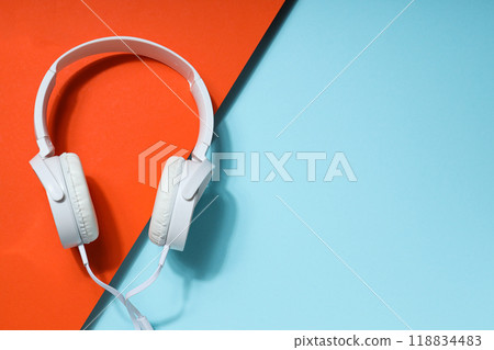 White, full-size wired headphones on a blue-orange background. White, full-size wired headphones on a blue-orange background. 118834483
