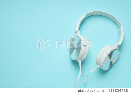 White, over-the-ear headphones with a wire on a blue background. White, over-the-ear headphones with a wire on a blue background. 118834488
