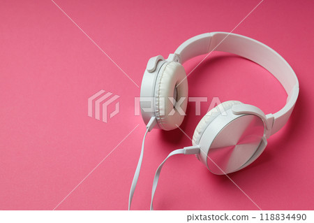 White, on-ear headphones with a wire on a pink background. White, on-ear headphones with a wire on a pink background. 118834490