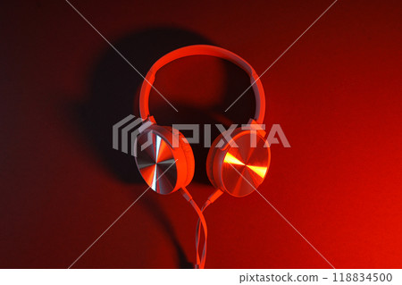White, over-the-ear headphones with a wire on a colored, dark background. 118834500