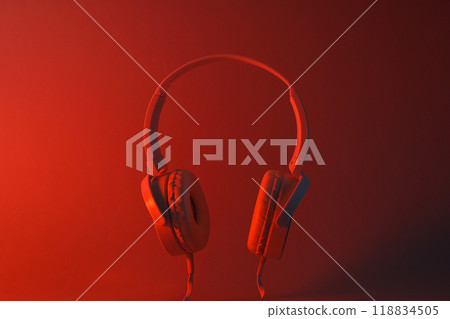 White, over-the-ear headphones with a wire on a colored, dark background. White, over-the-ear headphones with a wire on a colored, dark background. 118834505