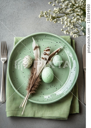 Decorative green eggs on a plate with fresh leaves and cutlery set for an Easter celebration 118834980
