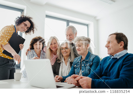 Teacher explaining senior students how to work with laptop, internetbanking. Elderly people attending computer and technology education class. Digital literacy. 118835254