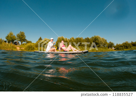 Women Enjoying Paddleboarding on a Sunny Day Women Enjoying Paddleboarding on a Sunny Day 118835527