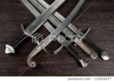 Swords and sabre on wooden background. 118836877