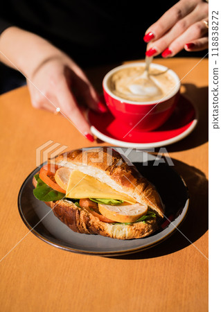 A woman drinks coffee with a croissant in a cafe A woman drinks coffee with a croissant in a cafe 118838272