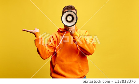 Man shouting to megaphone, shrugging as if making statement or raising awareness against sunny yellow background. Man shouting to megaphone, shrugging as if making statement or raising awareness against sunny yellow background. 118838376