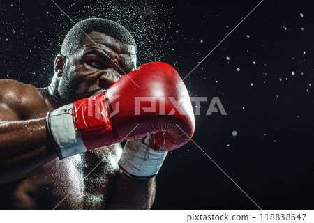 Intense African-American man, boxer wearing red gloves, in mid-punch, embodying raw power and energy of the fight. Intense African-American man, boxer wearing red gloves, in mid-punch, embodying raw power and energy of the fight. 118838647