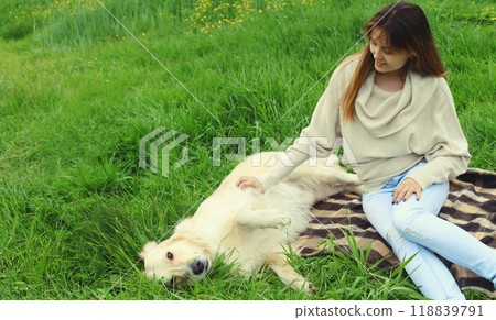 Happy owner young woman with Golden Retriever dog sitting on grass together in summer park 118839791