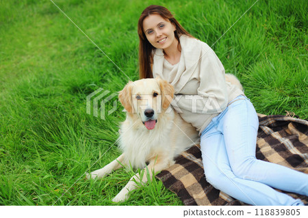 Happy owner young woman with Golden Retriever dog sitting on grass together in summer park 118839805