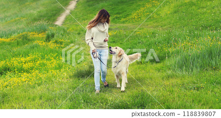 Owner woman walking with Golden Retriever dog on leash in summer park Owner woman walking with Golden Retriever dog on leash in summer park 118839807