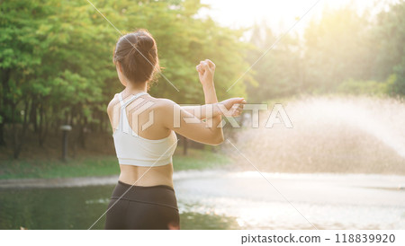 Female jogger. Fit young Asian woman with sportswear stretching muscle in park before running and enjoying healthy outdoor. Fitness runner girl in public park. Wellness being concept Female jogger. Fit young Asian woman with sportswear stretching muscle in park before running and enjoying healthy outdoor. Fitness runner girl in public park. Wellness being concept 118839920