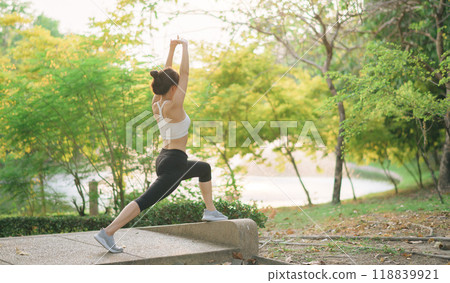Female jogger. Fit young Asian woman with sportswear stretching muscle in park before running and enjoying healthy outdoor. Fitness runner girl in public park. Wellness being concept 118839921