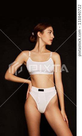 Posing with quiet confidence, woman gazes into distance, her profile emphasizing her graceful neck and shoulders against black studio background. Posing with quiet confidence, woman gazes into distance, her profile emphasizing her graceful neck and shoulders against black studio background. 118840722