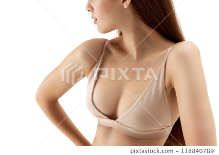 Close-up of female upper body, showing her flawless skin and delicate structure of her nude bra against white studio background. Close-up of female upper body, showing her flawless skin and delicate structure of her nude bra against white studio background. 118840789