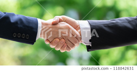Businessmen shaking hands outdoors, fresh greenery, hands Businessmen shaking hands outdoors, fresh greenery, hands 118842631