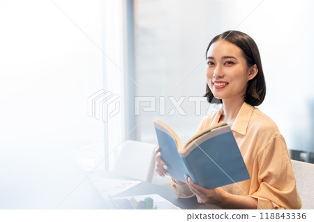 A woman with a smiling face turns her gaze towards me between reading 118843336