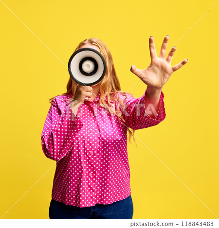 Time limited offers. Blonde woman in pink blouse, talking in megaphone and gesturing against yellow studio background 118843483