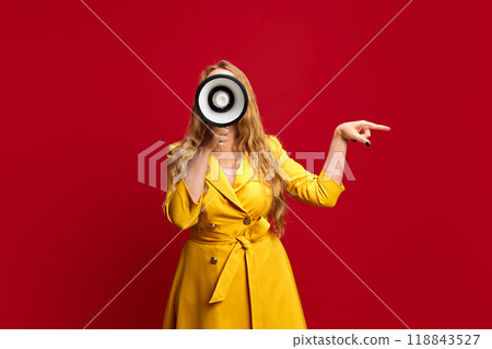 Young woman, with megaphone in hand, energetically announcing flash sale, signaling urgency and excitement against red studio background 118843527