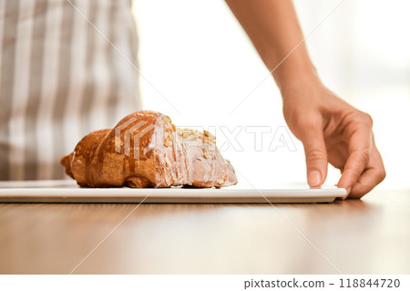female hand holding fresh handmade croissant on white plate 118844720