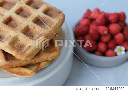Belgian or Viennese waffles with strawberries on minimalistic concrete grey background. delicious sweet dish Belgian or Viennese waffles with strawberries on minimalistic concrete grey background. delicious sweet dish 118845611