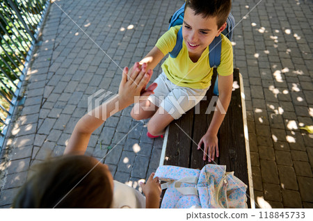 Smiling children giving high five outside on a sunny day Smiling children giving high five outside on a sunny day 118845733