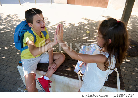 Two children sharing a high five at a park bench Two children sharing a high five at a park bench 118845734