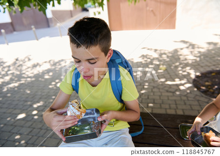 Young boy enjoying lunch outdoors on a sunny day at school 118845767