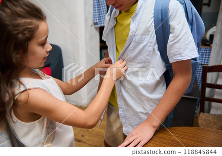 Young girl helps her brother button his shirt for school Young girl helps her brother button his shirt for school 118845844