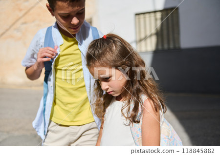 Young girl and boy with backpacks walking outdoors 118845882
