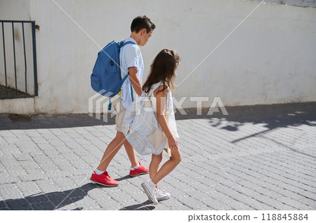 Children walking to school with backpacks under sunny skies 118845884