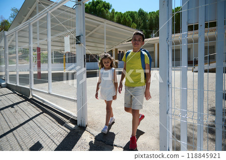 Smiling kids leaving school building on sunny day Smiling kids leaving school building on sunny day 118845921