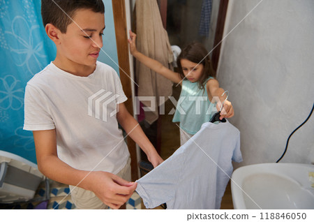 Siblings helping with laundry duties in a domestic setting Siblings helping with laundry duties in a domestic setting 118846050